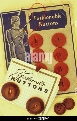 Vintage dressmakers cards with red buttons attached and captioned Fashionable buttons with sewing needle with red cotton Stock Photo