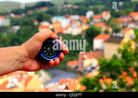 A tourist holds a compass in his hand against background of ancient city in valley. Travel, vacation and hiking. Summer, spring break, recreation Stock Photo