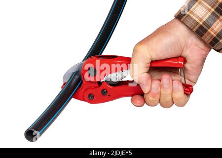 Plumber tools isolated. A man accurately cuts a piece of PE pressure pipe or water pipe with a red pvc pipe cutter. Clipping path. Drinking and servic Stock Photo