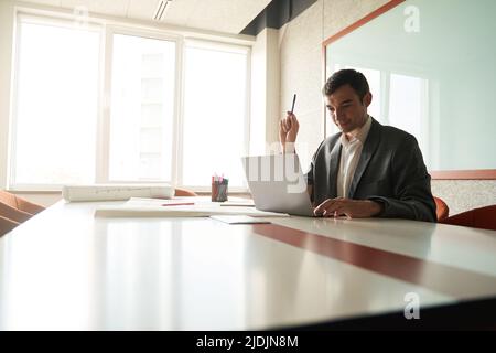 Designer holding pencil while working on laptop at table Stock Photo