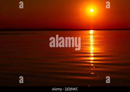 Red or orange sunset over the lake. Calm waves on the lake. Nature or quote or hope or hell concept photo. Tuz Golu in Turkey. Stock Photo