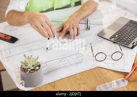 Closeup of hands of builder drawing renovation house equipment architects on the desk with a blueprint using compass, ruler and pen in the office. Concept of architects, construction, design. Stock Photo