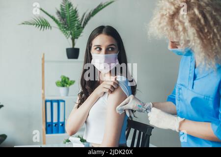 Doctor disinfecting skin on patient's arm before giving Covid-19 or flu vaccine. Coronavirus vaccination. Pandemic prevention. Stock Photo