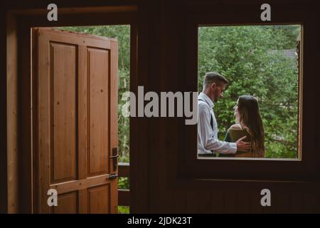 View from the window of the bride and groom sitting on the balcony, talking and spending the day together. Lifestyle moment. Romantic moment. Stock Photo