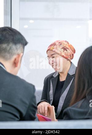 Asian businesswoman smiling while talking to customers. Modern office setting. Stock Photo