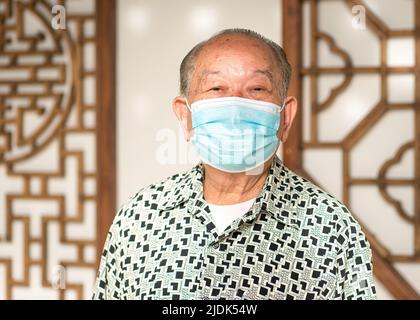 Senior man, Asian Chinese ethnicity. Wearing medical face mask. Portrait, close up shot. Stock Photo