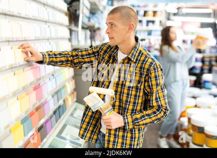 Young male customer choosing paint color for renovation works Stock Photo