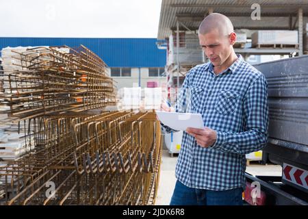 Man worker with papers collecting order at warehouse Stock Photo