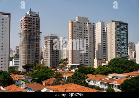 Big modern apartment buildings with others under construction between the houses of Agua Branca district under sunny clear blue sky. Stock Photo