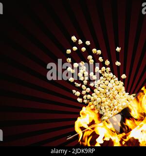 Flying popcorn on a dark background. Hot popcorn flying from pot under fire. Advertising concept. Stock Photo