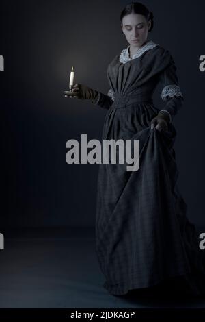 A Victorian maid servant or working class woman wearing a dark green checked bodice and skirt Stock Photo