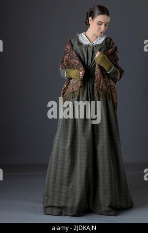 A Victorian maid servant or working class woman wearing a dark green checked bodice and skirt Stock Photo