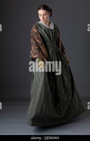 A Victorian maid servant or working class woman wearing a dark green checked bodice and skirt Stock Photo