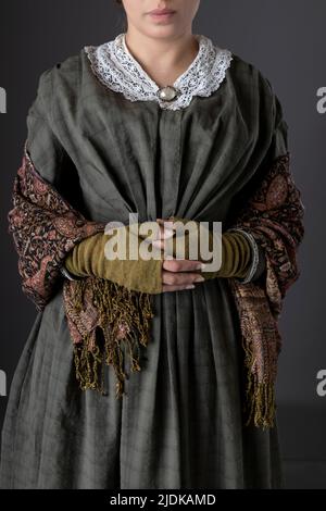 A Victorian maid servant or working class woman wearing a dark green checked bodice and skirt Stock Photo