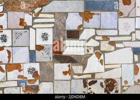 The background in the form of pieces of old different ceramic tiles laid on concrete plaster. Stock Photo