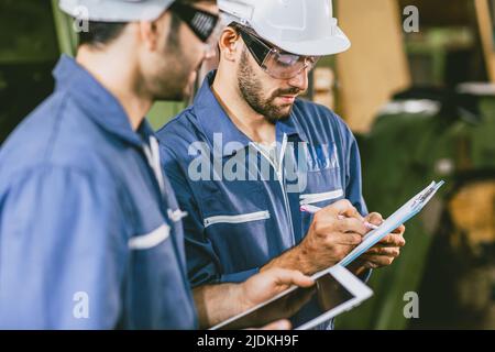 Team Industry Engineers worker in metal Factory using Digital Tablet Computer talking discussion help together. Stock Photo