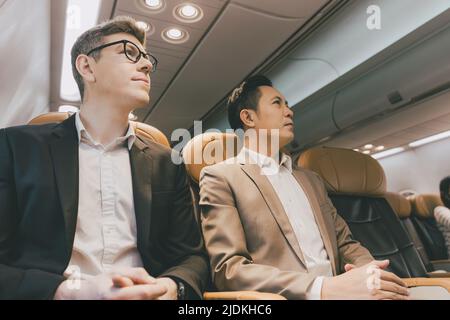 businessman mix race in flight on board cabin row together. Stock Photo