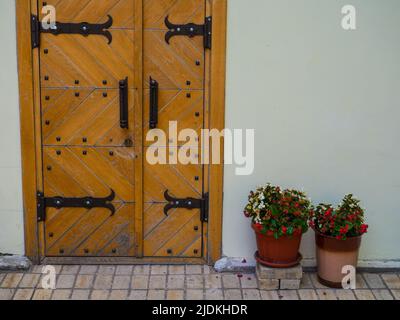 Ancient wooden door with iron rivets at wall of white building Stock Photo