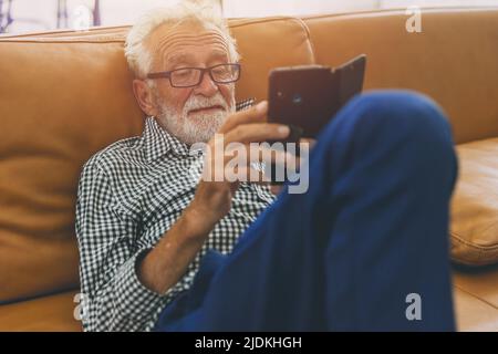 senior elderly man relax sitting enjoy using mobile phone lifestyle with smartphone addict in mature people concept. Stock Photo