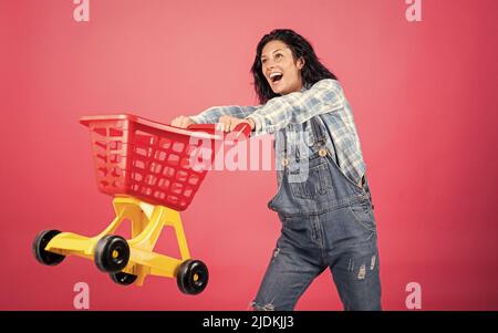 Nice purchase. Female housewife with shopping trolley in supermarket. girl pushing shopping cart in the mall. happy woman carry shopping cart. shopper Stock Photo