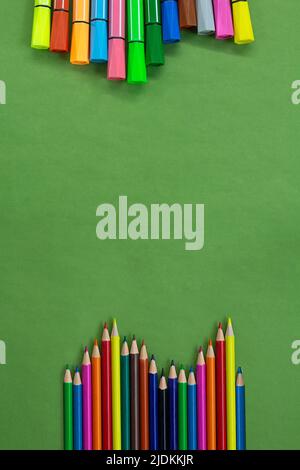 Colored felt tip pens and pencils in a row at the bottom and top or side with empty space for text on green. Back to school concept, drawing. Copy spa Stock Photo