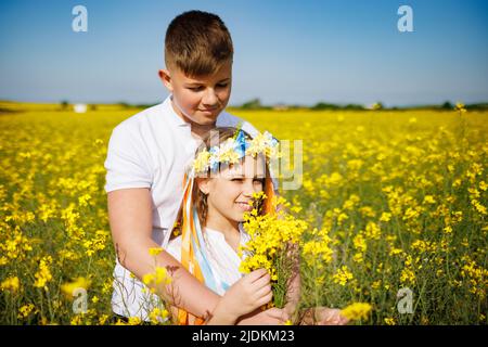 Brother hugs sister with Ukrainian wreath and bouquet of flowers in ...