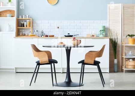 Minimal side view of elegant table and chairs set in wood with black detail in minimal kitchen interior, copy space Stock Photo