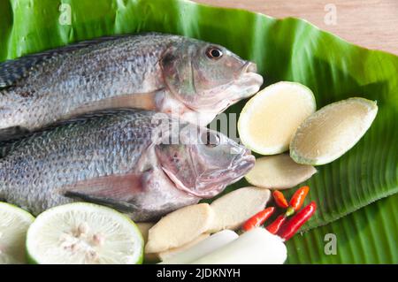 To view of fresh tilapia fish with lemongrass, lemon and chili on banana leaf. Asian food concept Stock Photo