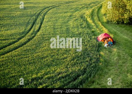 Aerial view on green field and couple traveling with tent Stock Photo