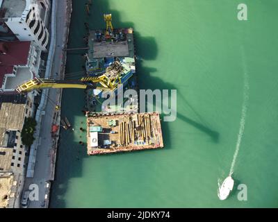 Floating crane dredging barges working on the construction of a marina. Aerial top view Stock Photo