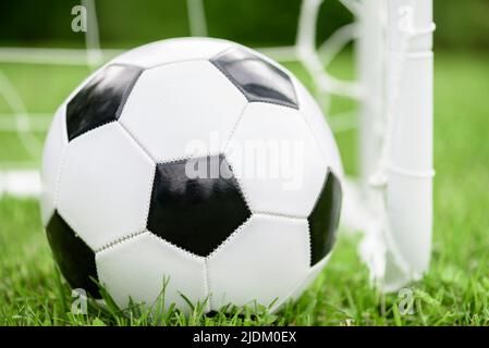 Generic black and white football (soccer) ball next to mini goal Stock Photo