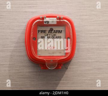 red fire alarm switch on concrete wall in office building. Industrial fire warning system equipment for emergency. Stock Photo