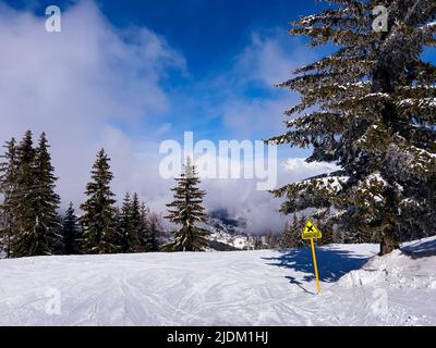 Ski track with crossing yellow sign over high altitude clouds Stock Photo