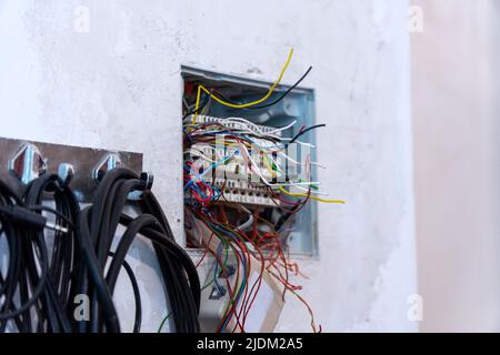 Open junction box with protruding wires, prepared for mounting and connecting telephone and computer cables. Selective focus Stock Photo