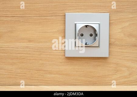 Close-up of silver plastic socket on the wooden wall above a desk Stock Photo