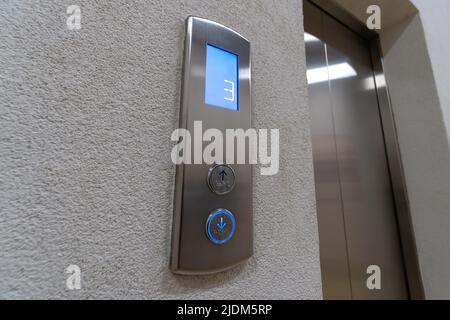 Close-up of the elevator call buttons up and down with Braille. Arrow of the elevator shows down the movement of the elevator to the third floor Stock Photo