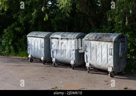 street trash can on wheels stands against the background of trees. High quality photo Stock Photo