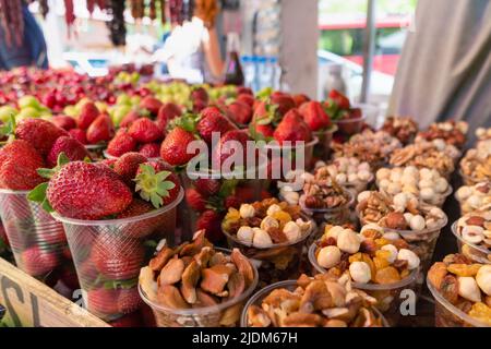 Close-up of strawberries, nuts, dried fruits, cherries, medlar in plastic cups. Counter with fruits, berries and dried fruits, a tourist place. Stock Photo