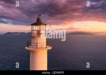 Lighthouse on the mountain peak at colorful sunset in summer Stock Photo