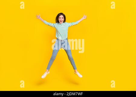 Full size photo of cheerful good mood rejoiced girl jumping have fun during vacation isolated on yellow color background Stock Photo