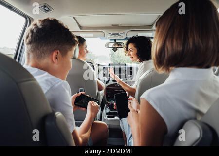 Happy Four Members Family Traveling by Minivan Car, Mother and Father with Two Teenage Children on a Weekend Road Trip Stock Photo