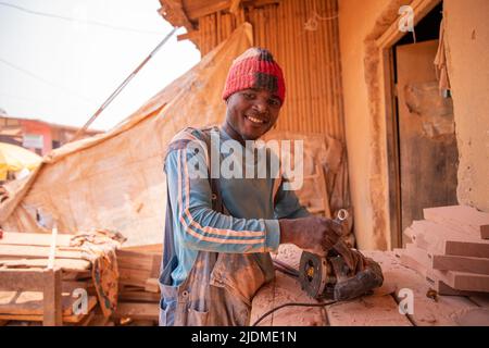 An african carpenter uses a chainsaw shaper in his workshop while working Stock Photo