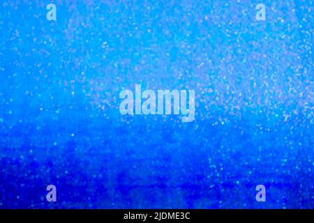 Defocused surface of shiny metallic wrapping film with color gradient from intense neon dark blue to light blue. Large amount of bokeh. Abstract backg Stock Photo