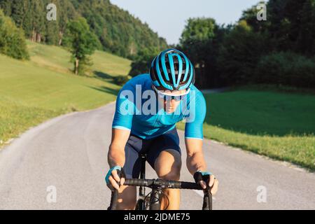 Professional road cycling male racer taking an aerodynamic body position for sprinting on a bike, front view. Stock Photo