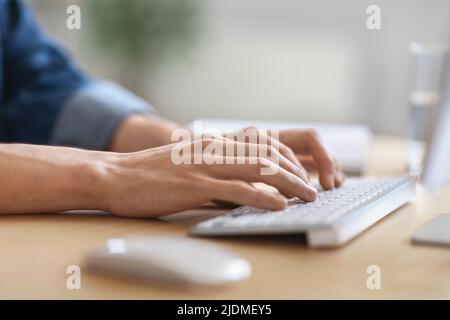 Unrecognizable male employee working on laptop at desk in office Stock Photo
