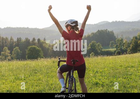 Caucasian girl cyclist with professional racing sports gear riding on an open road cycling route Stock Photo