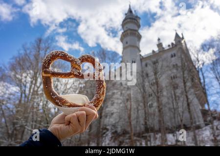 eating huge bavarian pretzel next to the Neuschwanstein castle Stock Photo