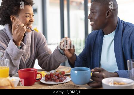 Romantic african american mid adult couple holding hands while having breakfast at dining table Stock Photo