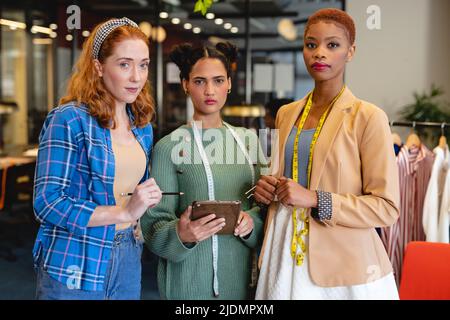 Portrait of confident multiracial female fashion designers working in creative office Stock Photo