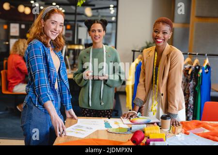 Portrait of happy multiracial female fashion designers working in creative office Stock Photo